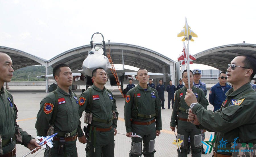 ↑艦載航空兵某部司令員戴明盟向飛行員演示空中飛行注意事項(xiàng)。